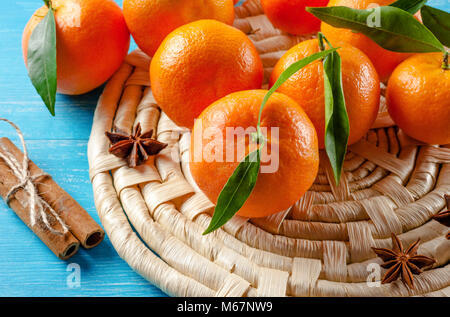 Mandarinen mit Blättern und Zimt auf Holz- Hintergrund Stockfoto