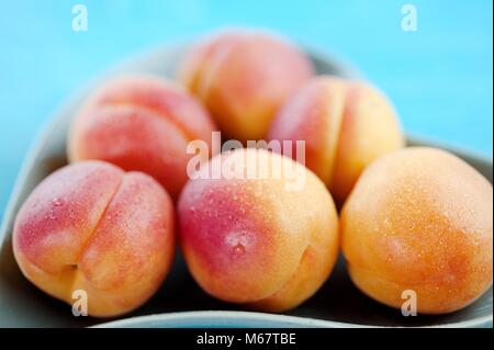 Pfirsiche köstliche Frucht in Herzform Teller auf einem blauen vintage Holz- Hintergrund Stockfoto