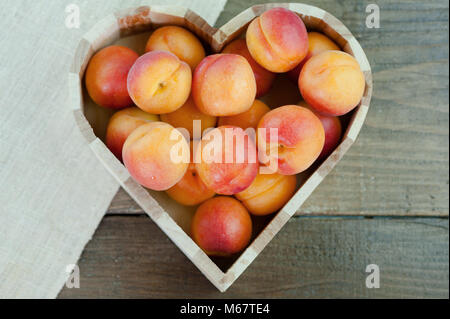 Pfirsiche reif Frische gesunde Frucht in Herzform Schüssel auf einem hölzernen Hintergrund Stockfoto