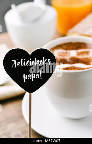 Einen herzförmigen Schild mit dem Text papa felicidades, herzlichen Glückwunsch Daddy auf Spanisch geschrieben, und eine Tasse Cappuccino mit einer Brille eine Stockfoto