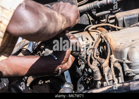 Close-up auf einem afrikanischen Mann bei der Arbeit auf einem defekten Auto Motor, Ouagadougou, Burkina Faso. Stockfoto