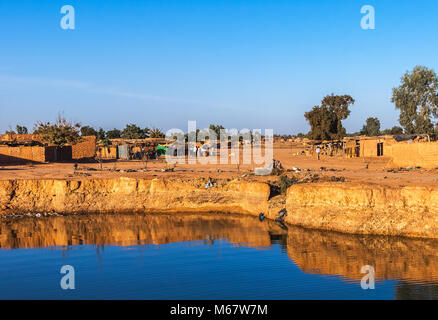 Eastern Township von Ouagadougou an einem sonnigen Tag mit einer Bohrung mit Regenwasser im Vordergrund gefüllt, Burkina Faso. Stockfoto