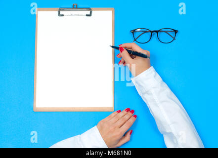 Ansicht von oben Büro Schreibtisch. Frau schreiben auf Dokument Arbeitsbereich mit weiblichen Händen, Zwischenablage Stockfoto