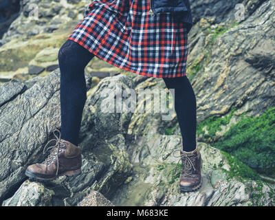 Die Beine einer jungen Frau trägt einen Rock steht auf ein paar Felsen in der Natur Stockfoto