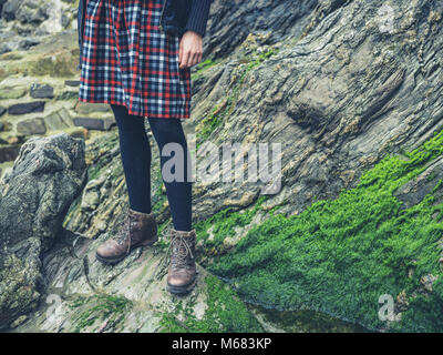 Die Beine einer jungen Frau trägt einen Rock steht auf ein paar Felsen in der Natur Stockfoto