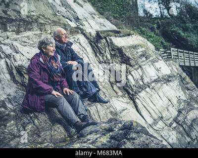 Ein älteres Paar sitzt auf den Felsen am Meer Stockfoto