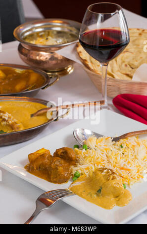 Indische Curry essen verteilen sich auf ein phantastisches Abendessen Tabelle mit Reis, laccha Paratha, Lamm aam Wala, Safran Malai Kofta, Rotwein. Stockfoto