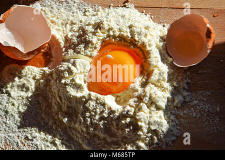 Schließen Sie bis zu Eigelb in weißes Mehl mit gebrochenen Eierschalen auf Holz board Stockfoto