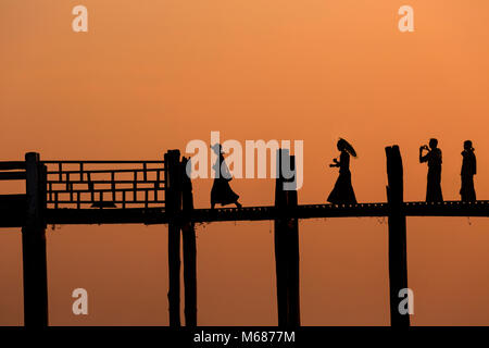 Silhouetted zahlen Kreuzung U-Bein Brücke, Ubein Brücke, über den Taungthaman See bei Sonnenuntergang, Amarapura, Mandalay, Myanmar (Birma), Asien im Februar Stockfoto