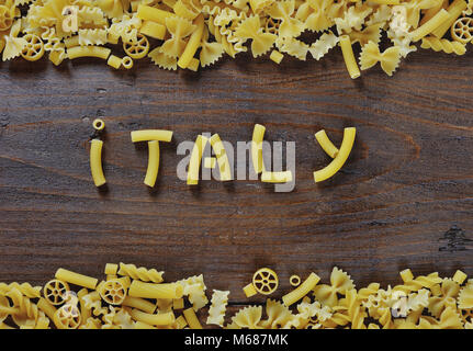 Italienische Pasta auf braunem Holz- Hintergrund - Italien Wort mit Pasta geschrieben Stockfoto