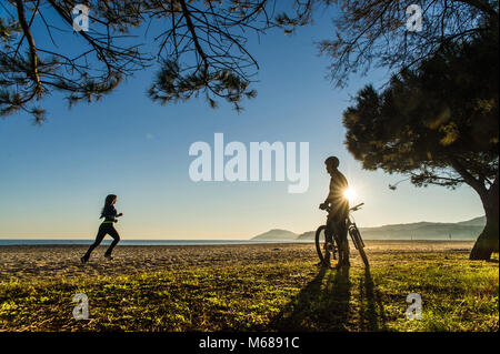 In Argeles-sur-Mer (Frankreich). Zwei junge Leute, ein Mountainbike und läuft entlang der Uferpromenade am frühen Morgen Stockfoto