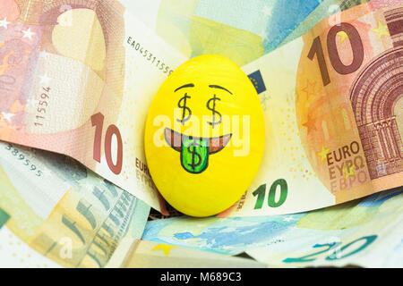 Emoji Osterei mit Gesichtsausdruck "Ich liebe Geld' auf Papiergeld Euro platziert. Stockfoto