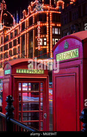 Harrods Kaufhaus in der Nacht in London Vereinigtes Königreich London mit roten Telefonzellen im Vordergrund Stockfoto