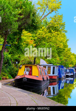 Boote und Kähne in Little Venice lodon Großbritannien mit Colurful Bäumen und schönen blauen Himmel und Reflexionen im Wasser Stockfoto