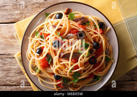 Spaghetti alla putanesca mit Sardellen, Tomaten, Knoblauch und schwarzen Oliven close-up auf einem Teller. horizontal oben Ansicht von oben Stockfoto