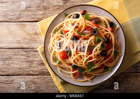 Traditionelle Pasta alla puttanesca mit Sardellen, Tomaten, Knoblauch und schwarzen Oliven close-up auf einem Teller auf den Tisch. horizontal oben Ansicht von oben Stockfoto