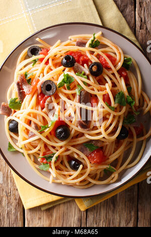Pasta alla Puttanesca mit Sardellen und schwarzen Oliven auf einem Teller. Vertikal oben Ansicht von oben Stockfoto