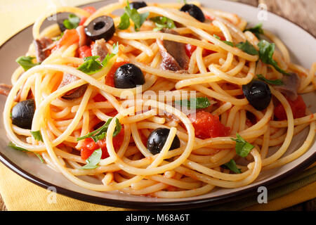 Pasta alla Puttanesca mit Sardellen und schwarzen Oliven Makro auf einem Teller. Horizontale Stockfoto