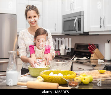 Glückliche Familie in der Küche, die Mutter und Tochter kochen Apfelkuchen, Mixen von Teig Stockfoto