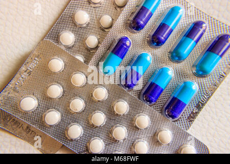 Blister Packung mit blau-lila Kapseln und weiße Tabletten auf weißem Hintergrund, in der Nähe Stockfoto