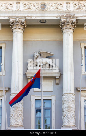 Venezianische geflügelte Löwe Skulptur und Stadt Flagge auf der Fassade des Rathauses in Piran, Slowenien Stockfoto