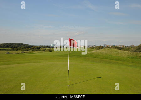 Blick zurück über 1. Grün mit Flagge zu Fahrrinne, Littlehampton Golf Club, Littlehampton, Sussex, England Stockfoto