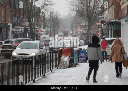 Verkehr und Menschen kämpfen bei Frost, betitelt "das Tier aus dem Osten' aufgrund der Sub Zero kalter Winde aus Sibirien, steigt auf Kings Heath High Street am 1. März 2018 in Birmingham, Vereinigtes Königreich. Stockfoto