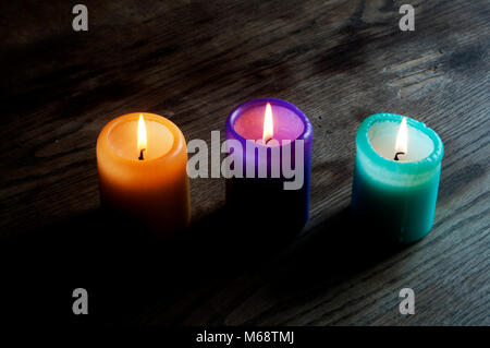 Drei bunten Kerzen an einem hölzernen Tisch Stockfoto
