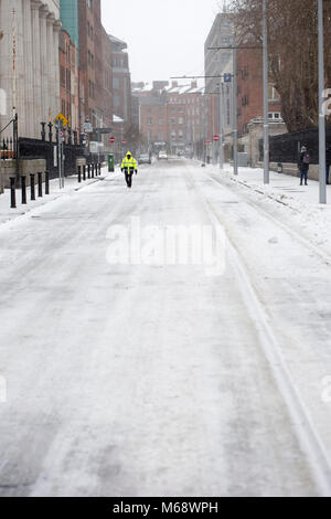 Mann zu Fuß im Stadtzentrum auf der Straße im Schnee bedeckt. Dublin/Irland. Tier aus dem Osten Stockfoto