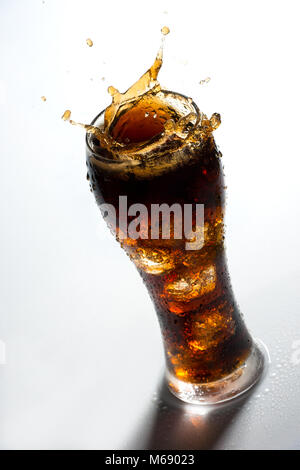 Eis Spritzer auf einem Glas Cola trinken gegen einen weißen Hintergrund Stockfoto
