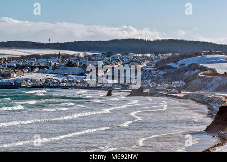 Küste von Moray in Schottland Cullen Bay mit einem stürmischen Meer WINTER SCHNEE AUF DER HÄUSER IN DER STADT Stockfoto