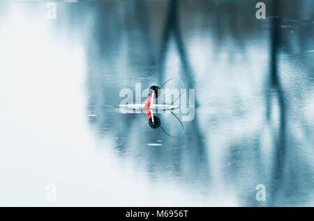 Ein angelgeräte für den Fang von Fischen ist auf einer Bohrung auf einer transparenten Brilliant Blue Ice installiert Stockfoto