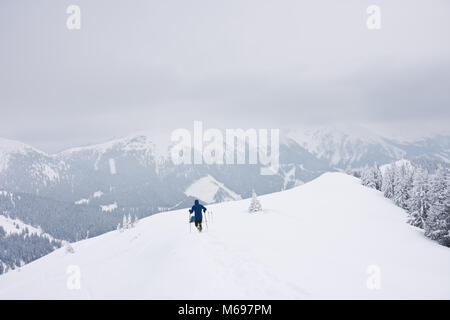 Ski Bergsteiger auf schneebedeckten Berg auf düsteren kalten Wintertag bei bewölktem Himmel im Hinterland von Österreich. Stockfoto