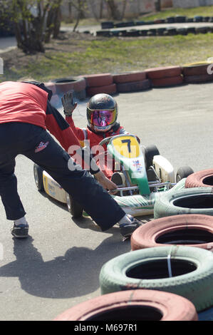 Kovrov, Russland. 24. April 2016. Go-kart Wettbewerbe im Sport die Abschnitte 'Rodina-Motor' auf dem Schulhof. Mann hilft Jungen gehen auf der Spur Stockfoto