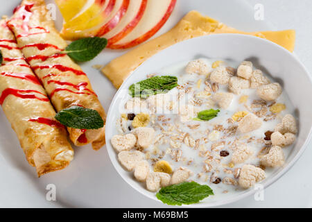 Frühstück mit Pfannkuchen, Äpfel, Käse und Müsli mit Milch. Stockfoto