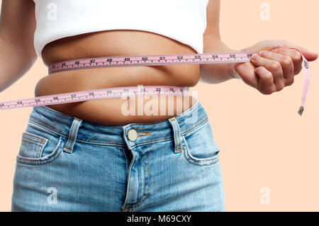 Übergewichtige Frau mit Maßband um Taille an den pastellfarbenen Hintergrund Stockfoto