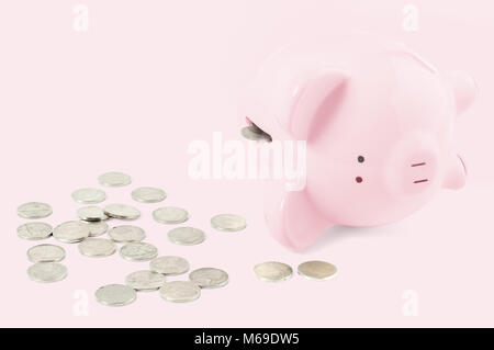 Leere rosa Sparschwein und Münzen am Pastell rosa Hintergrund Stockfoto