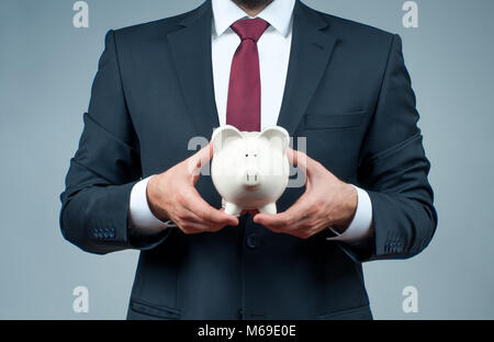 Geschäftsmann in Anzug hält Sparschwein. Finanzierung Einsparungen Konzept Stockfoto