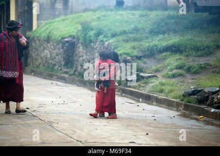 Ixil Maya Kinder Stop auf der Straße eine Frau in der traditionellen Kleidung zu sprechen. San Gaspar Chajul, Ixil Dreieck, Guatemala. Stockfoto