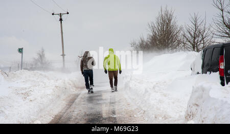 Zurück Blick auf zwei Menschen zu Fuß auf der Straße durch tiefe Schneeverwehungen am 24. März 2013 Stockfoto