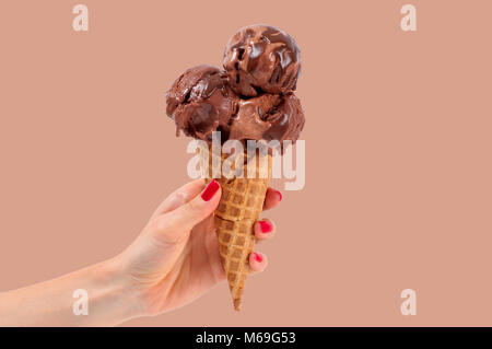 Schokolade Eis Konus pastellfarbenen Hintergrund. Hand mit Schokolade Eis in der Wafer Cup. Stockfoto