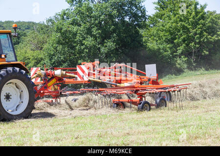 Nahaufnahme Detail eines landwirtschaftlichen rotierenden Rechen harken frisch geschnittene getrocknete Gras für Heu in eine landwirtschaftliche Weide hinter einem Traktor gezogen wird. Einige Stockfoto