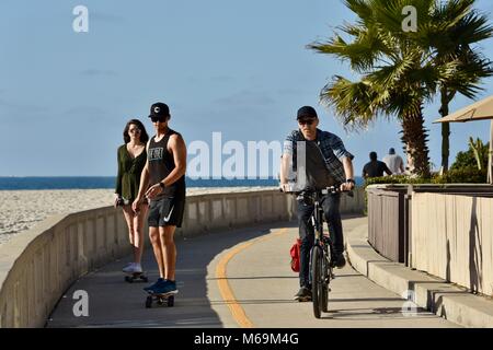 Man Radfahren und junges Paar skateboarding am beliebten Strand gepflasterten Promenade in Mission Beach, San Diego, Kalifornien, USA Stockfoto