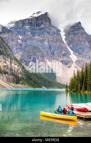 LAKE LOUISE, Kanada - 22.August 2014: Kanuten ihre Kanufahrt auf Moraine Lake vorbereiten mit Wolken absteigend auf das Tal der zehn Gipfel Stockfoto