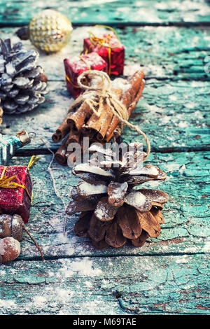 Geschenke und Dekorationen für Weihnachten auf hölzernen Hintergrund mit Tannenzapfen und Gewürzen bestreut Stockfoto