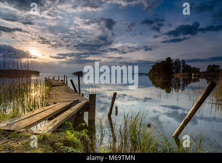 Alten hölzernen Steg in den See mit der Sonne im Hintergrund führende Stockfoto