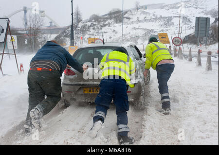 Brynmawr, Blaenau Gwent, South Wales, UK. 2. März, 2018. Zwei Männer aus einem Knirschen Fahrzeug und einem vorbeifahrenden Baggerfahrer stop einen gestrandeten Autofahrer in der Nähe von Leitern der Täler Road in der Nähe Brynmawr zu helfen. Menschen battlle gegen den Blizzard, Schneeverwehungen und horrenden Verschlechterung der Wetterverhältnisse wie Sturm Emma ungebrochen in Brynmawr in South Wales (die höchste Stadt in Wales.) © Graham M. Lawrence/Alamy leben Nachrichten Stockfoto