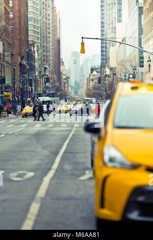 New York City, New York, USA - 19. Februar 2018: New York City street scene mit unscharfen gelbes Taxi im Vordergrund und Blick auf die Avenue. Stockfoto