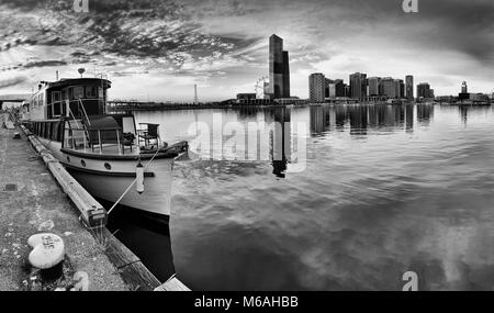 Moody bezauberndes Panorama von Melbourne Docklands mit Angedockten historisches Holzboot und entfernten modernen städtischen Türme reflektieren, noch Wasser von Yar Stockfoto