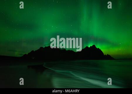 Die Aurora Borealis oder Northern Lights oben Stokksnes Berge und Vestrahorn mit dem Atlantischen Ozean im Vordergrund, im südlichen Island Stockfoto